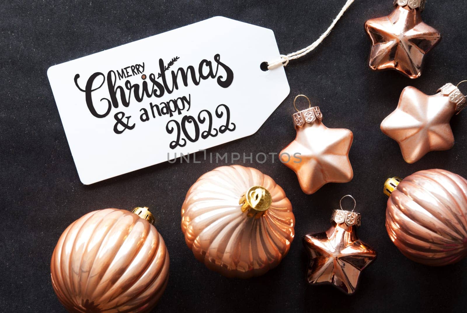 One Label With English Calligraphy Merry Christmas And A Happy 2022. Golden Christmas Ball Ornament On Black Background.