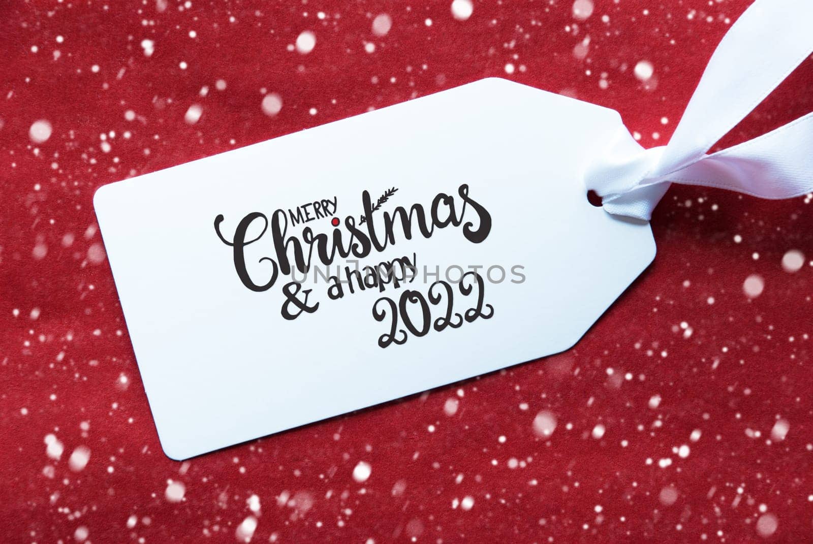 Label With English Calligraphy Merry Christmas And A Happy 2022. Red Textured Background With Snowflakes