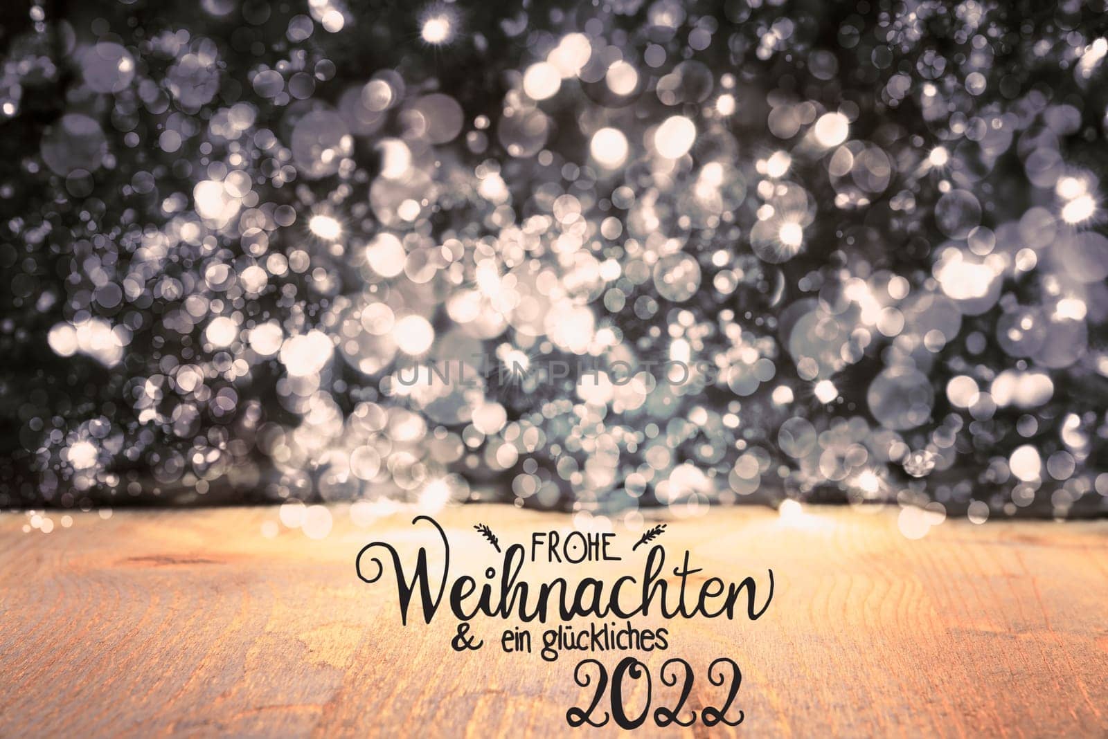German Calligraphy Frohe Weihnachten Und Ein Glueckliches 2022 Means Merry Christmas And Happy 2022. Black Christmas Background With Sparkling Lights And Wood