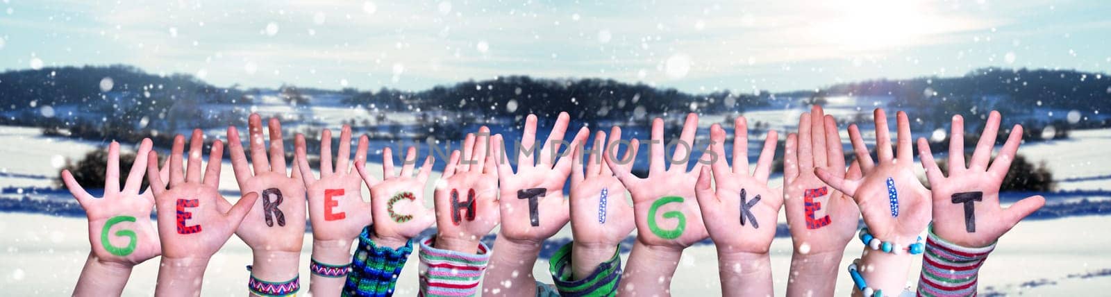 Children Hands Building Colorful German Word Gerechtigkeit Means Justice. Snowy Winter Background With Snowflakes