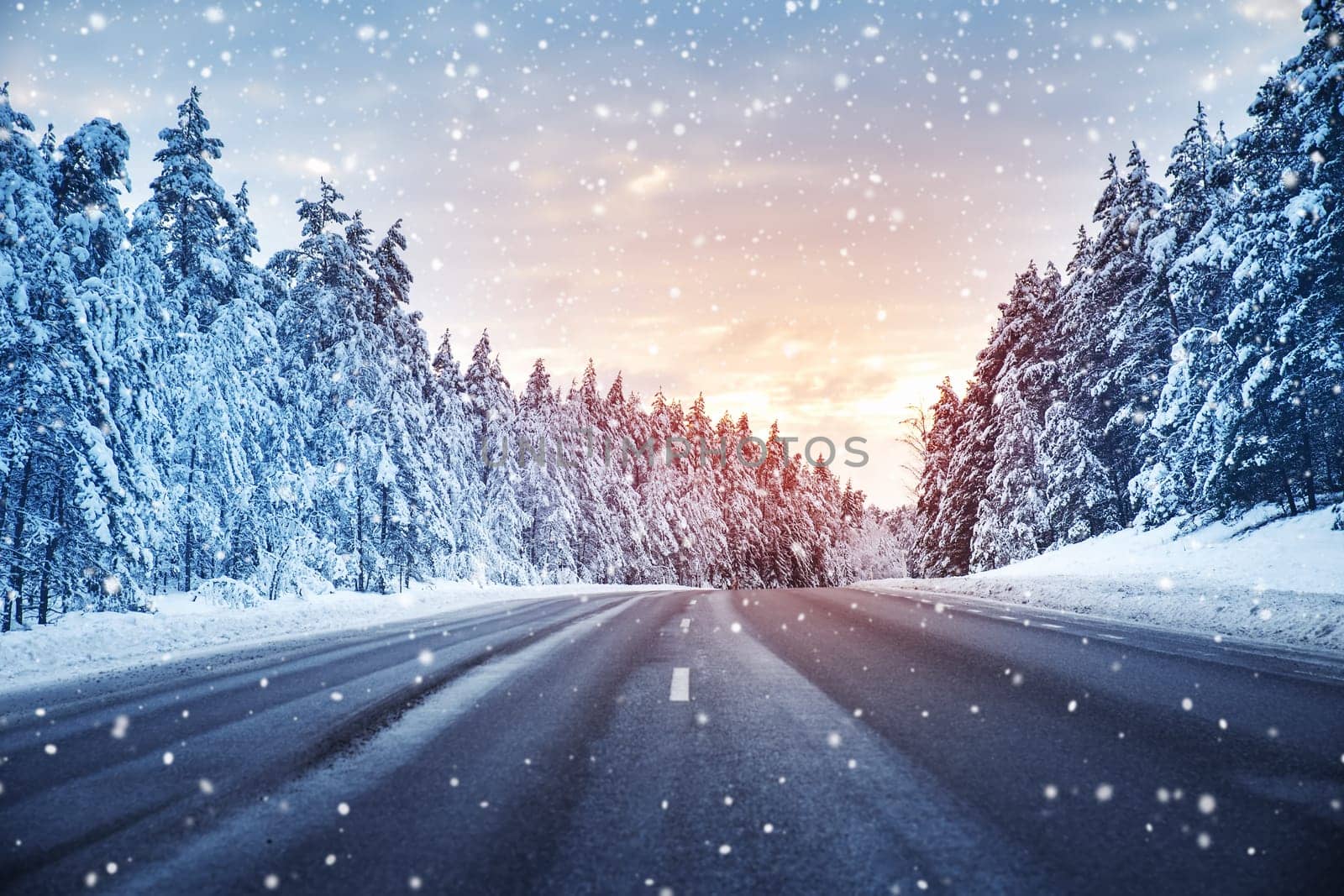 Beautiful view of the snowy curve country road in snowfall. Winter way in natural park.