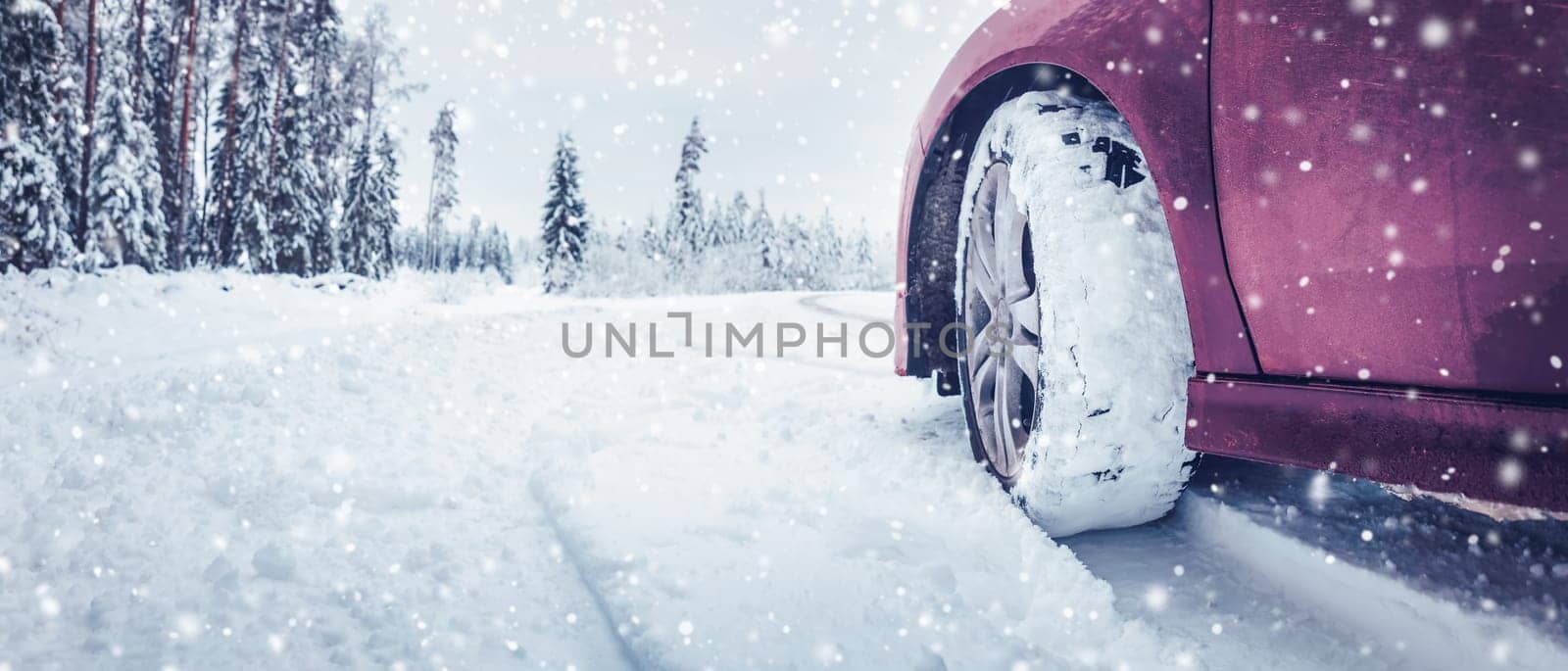 Panoramic view of the red car on the snowy road in snowfall.. Concept of the danger of driving on a winter road and travelling by auto in Christmas holidays.