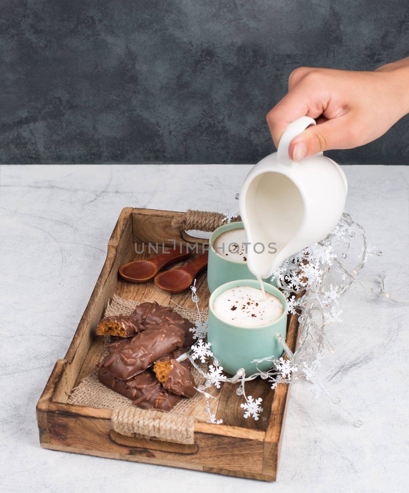 Coffee cups and chocolate coated gingerbread in a wooden basket, christmas season empty copy space, book with a pen