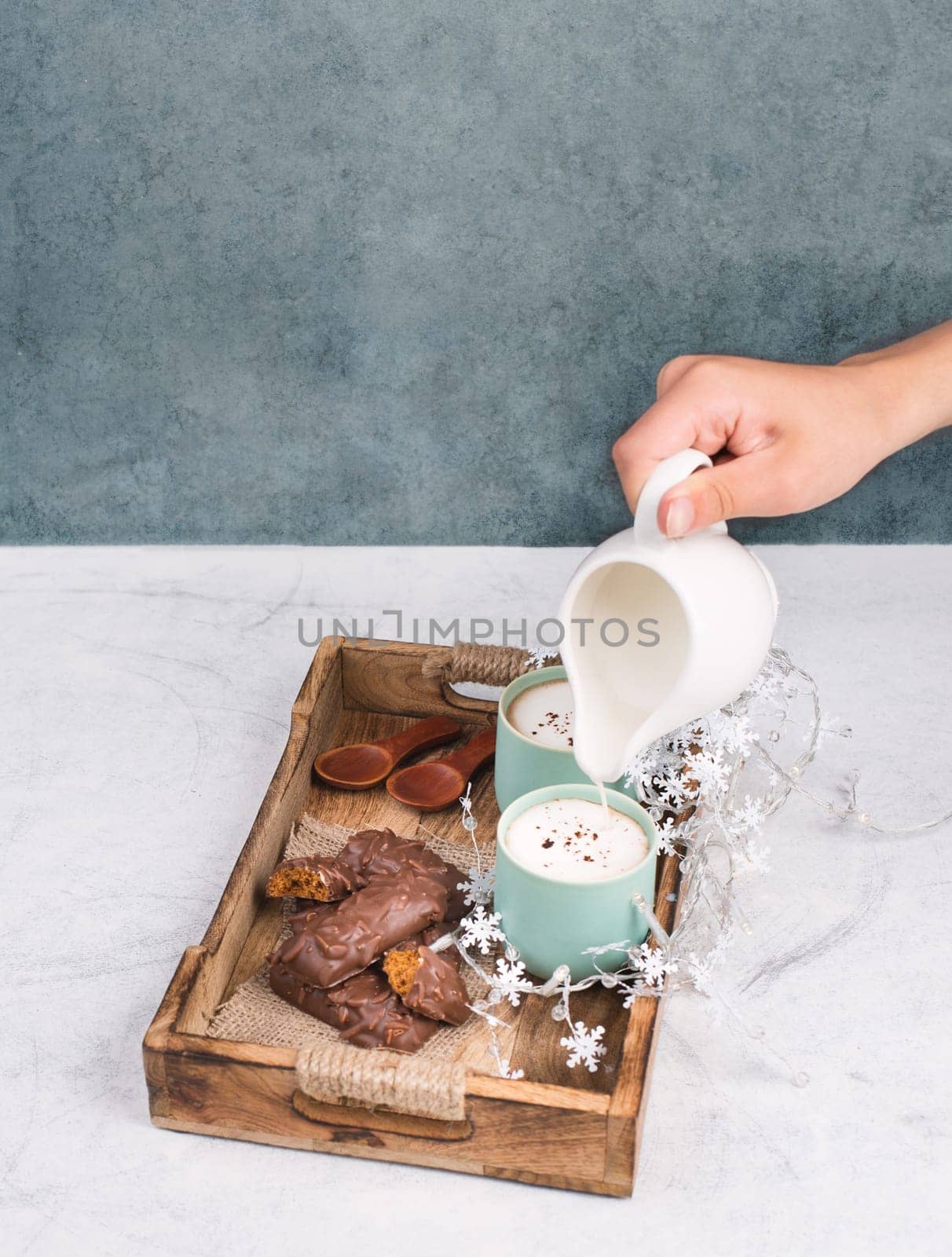 Coffee cups and chocolate coated gingerbread in a wooden basket, christmas season empty copy space, book with a pen