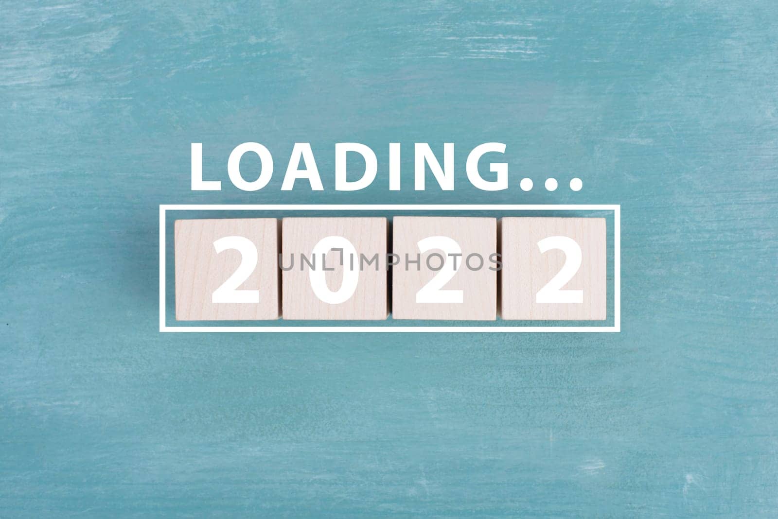 2022 is standing in white colored letters on wooden cubes, the word loading is standing above, blue background
