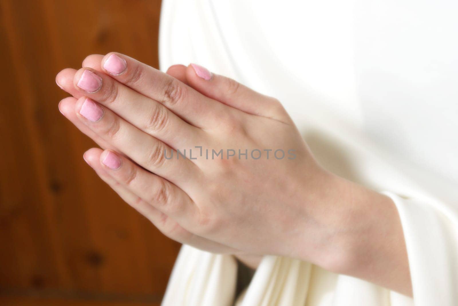 A young woman brings her hands together in prayer to the almighty father in heaven.
