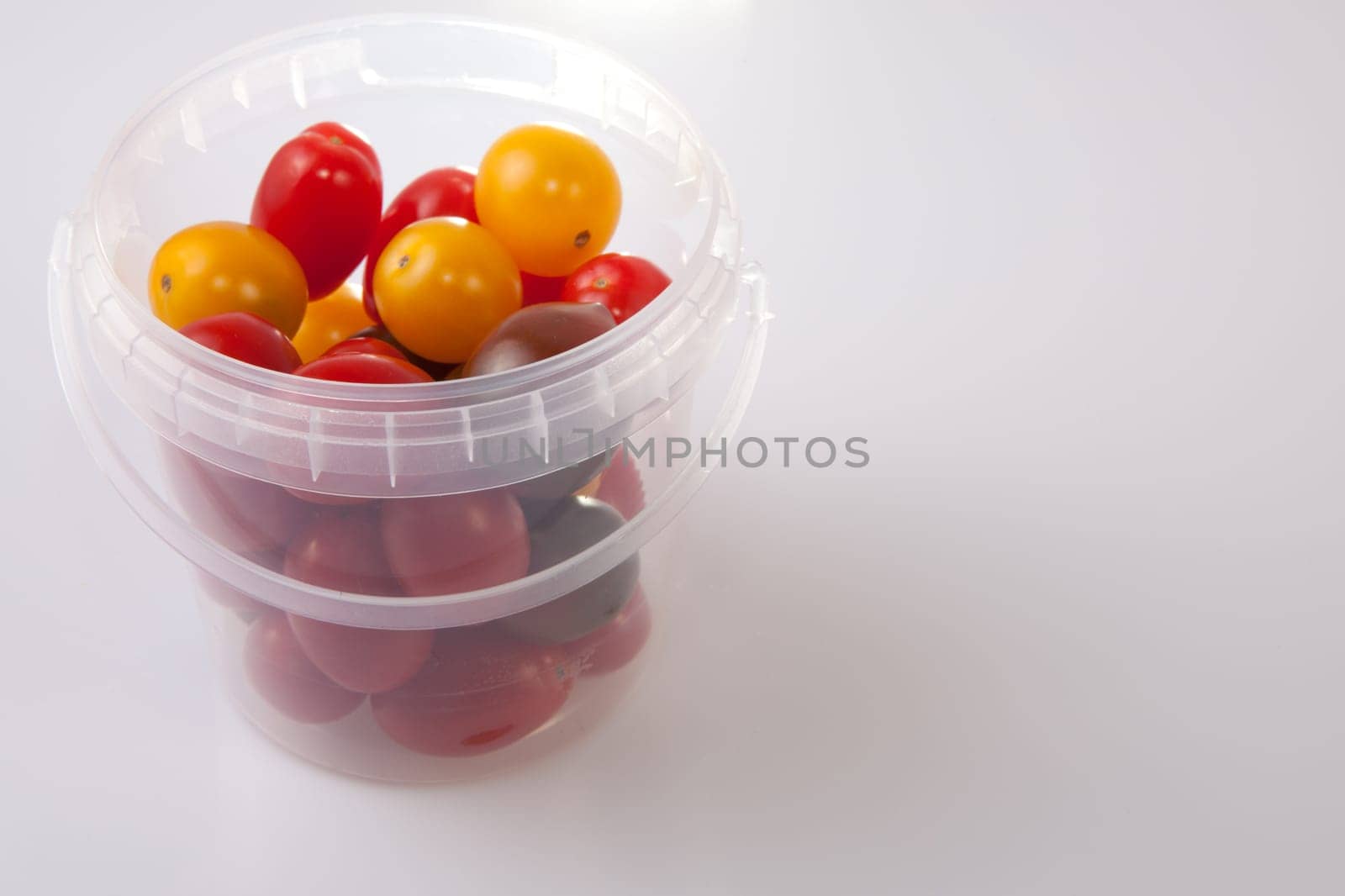 Bucket of colorful cherry tomatoes. Isolated over white background