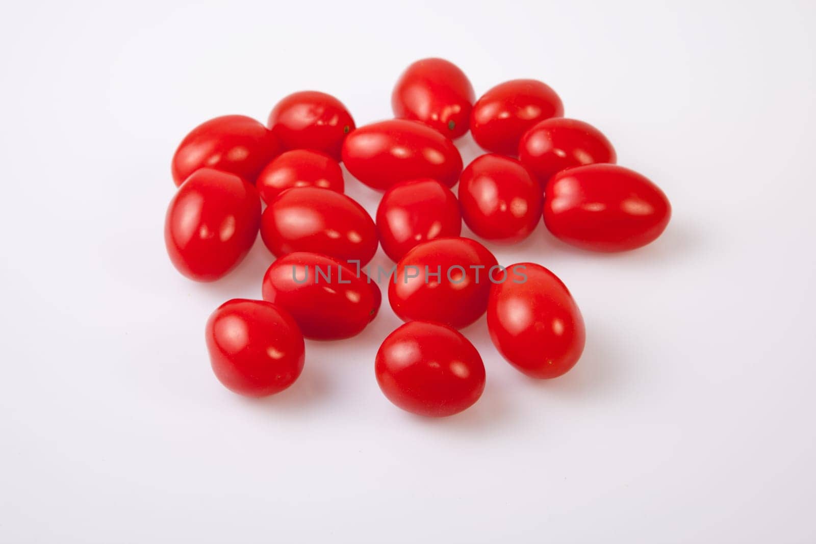 Handful of red shiny cherry tomatoes. Isolated over white background