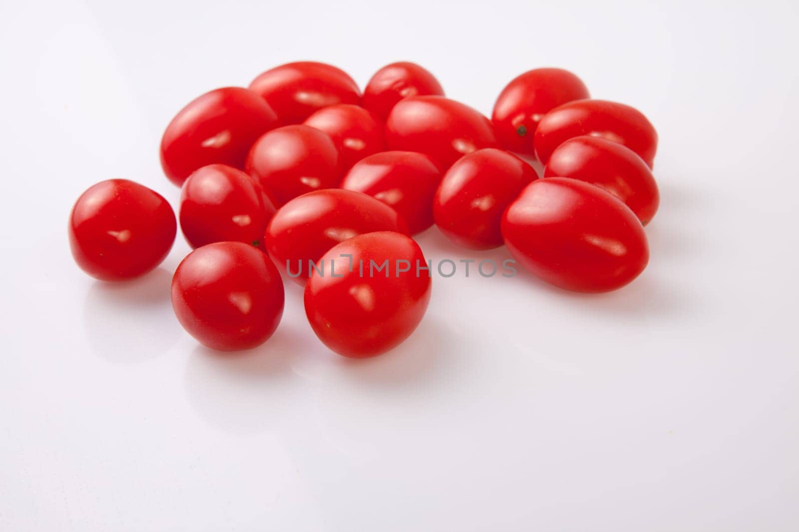 Handful of red shiny cherry tomatoes. Isolated over white background