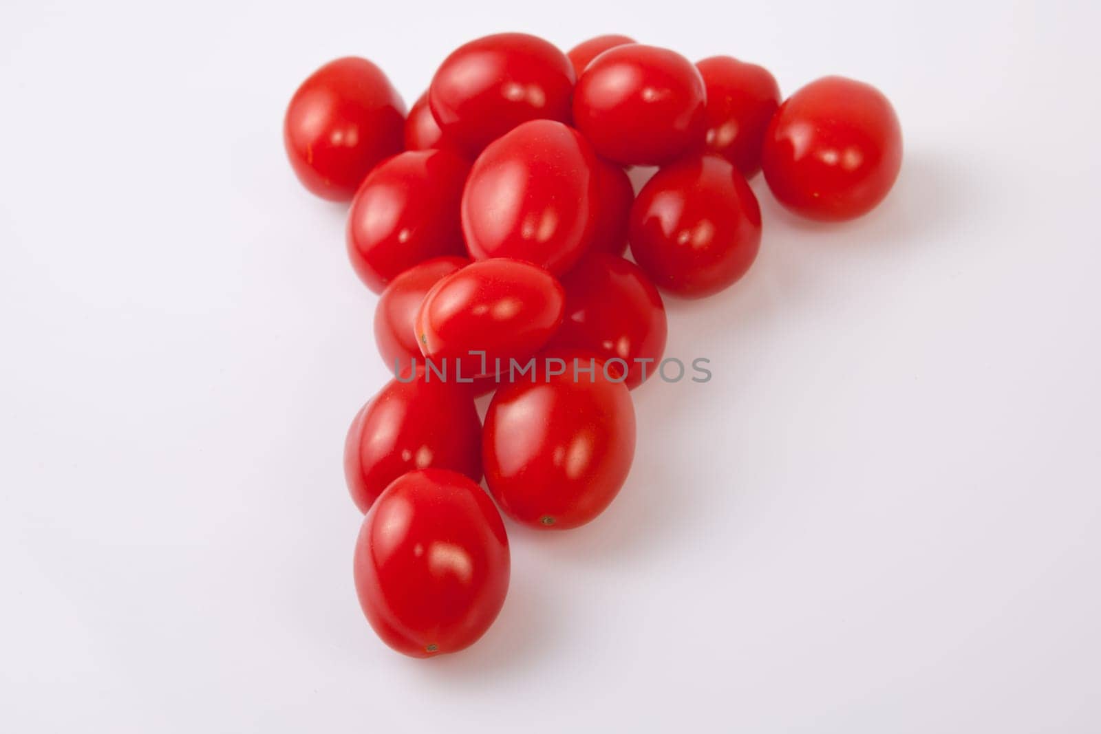 Handful of red shiny cherry tomatoes. Isolated over white background