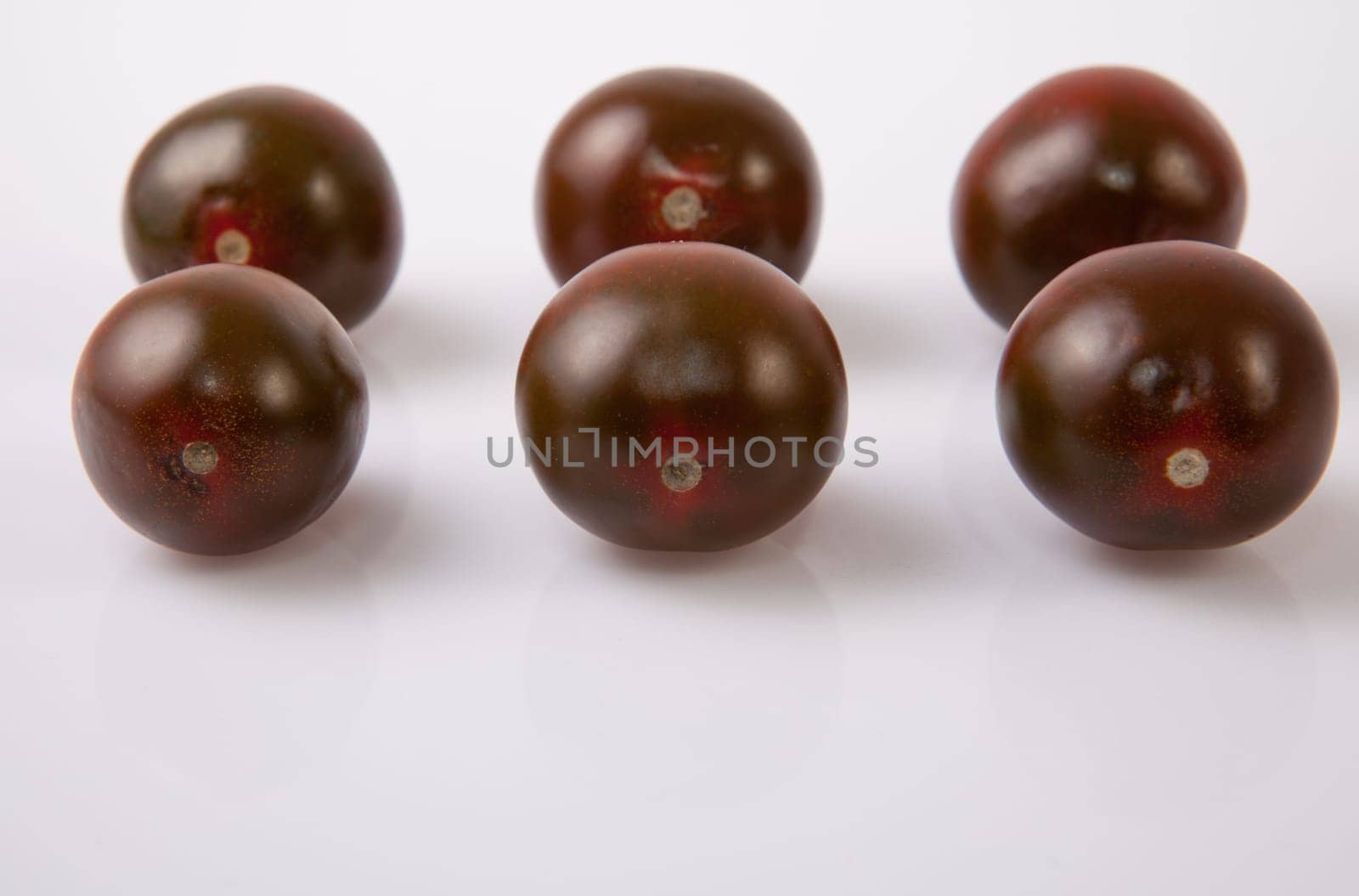 Dark green cherry tomatoes. Isolated over white background