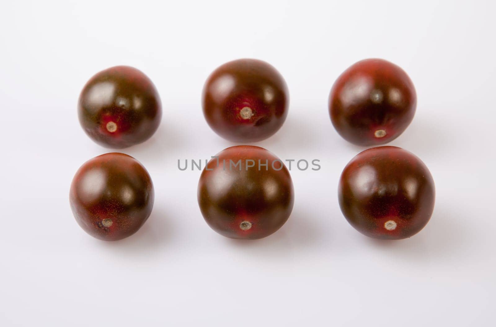 Dark green cherry tomatoes. Isolated over white background