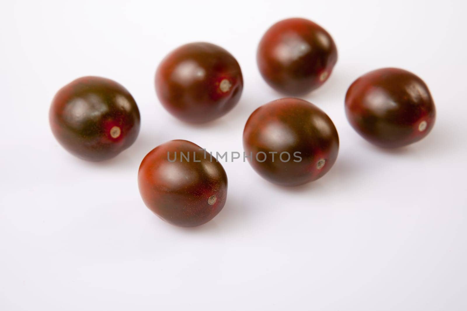 Dark green cherry tomatoes. Isolated over white background
