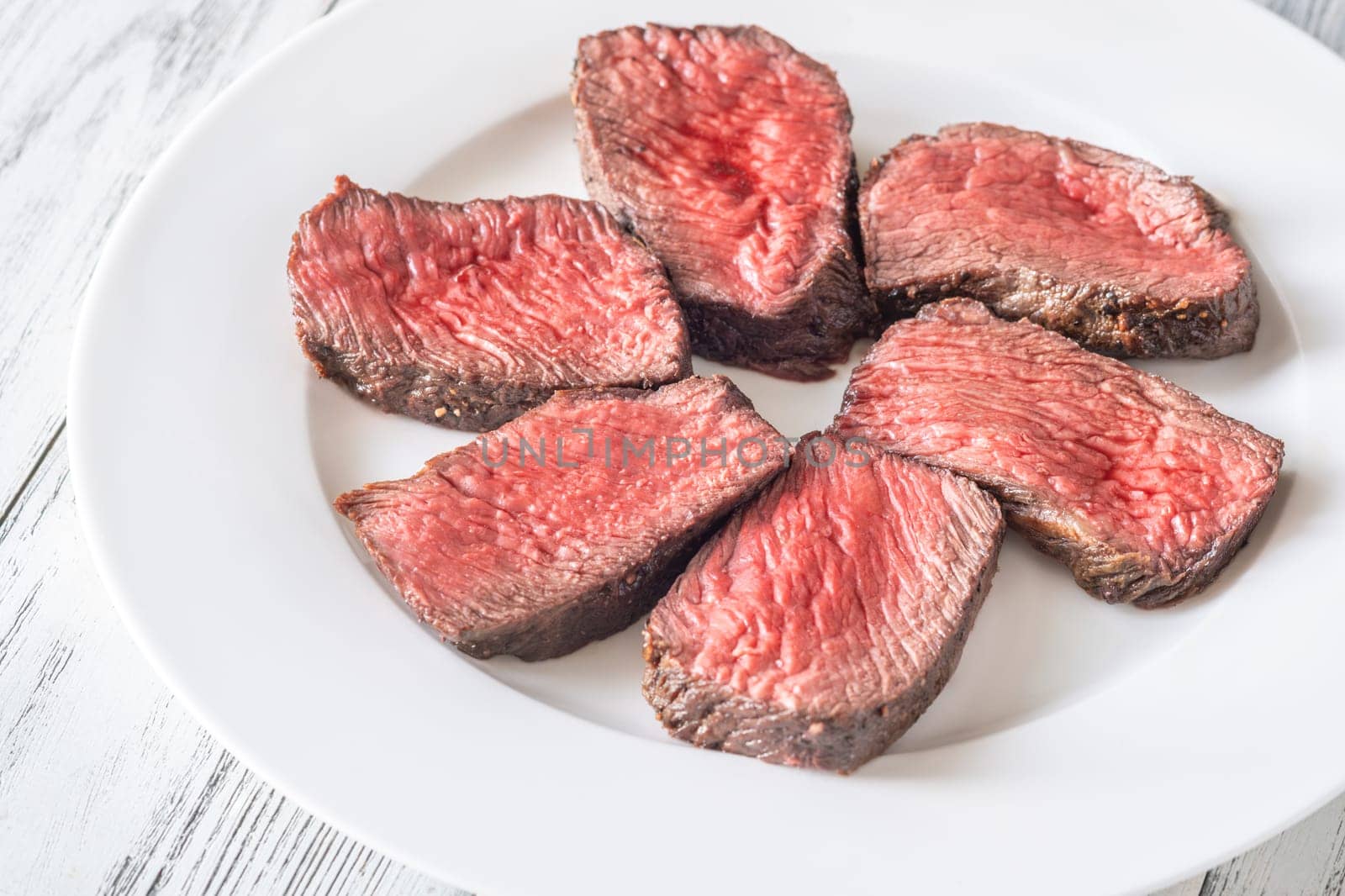 Tender fillet mignon steak, perfectly cooked, sliced, and elegantly presented on a plate