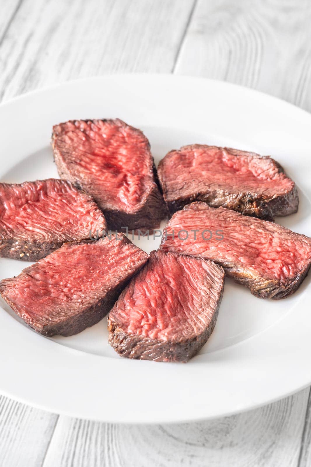 Tender fillet mignon steak, perfectly cooked, sliced, and elegantly presented on a plate