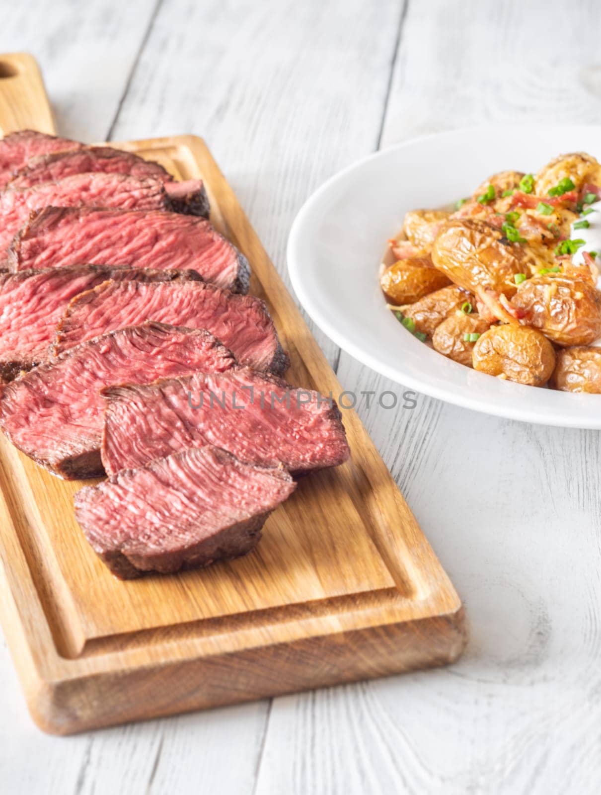 Perfectly sliced steak with golden potatoes, crispy bacon, gooey cheddar, and fresh onions