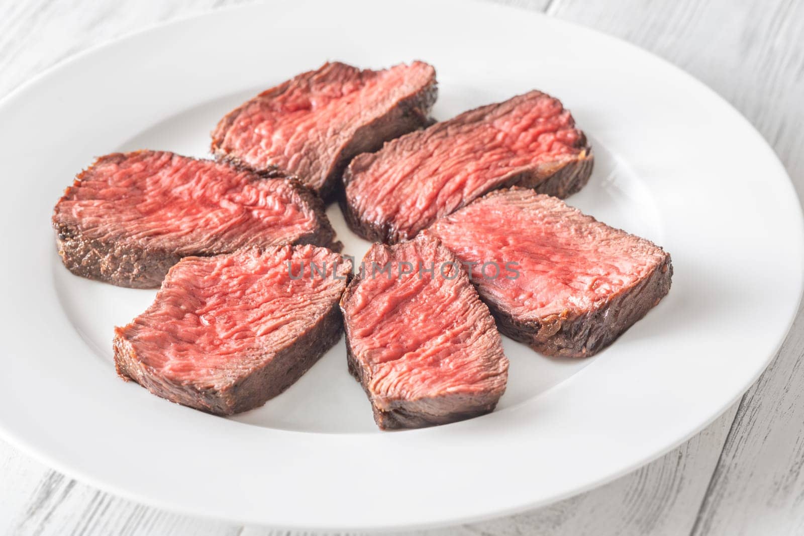 Tender fillet mignon steak, perfectly cooked, sliced, and elegantly presented on a plate