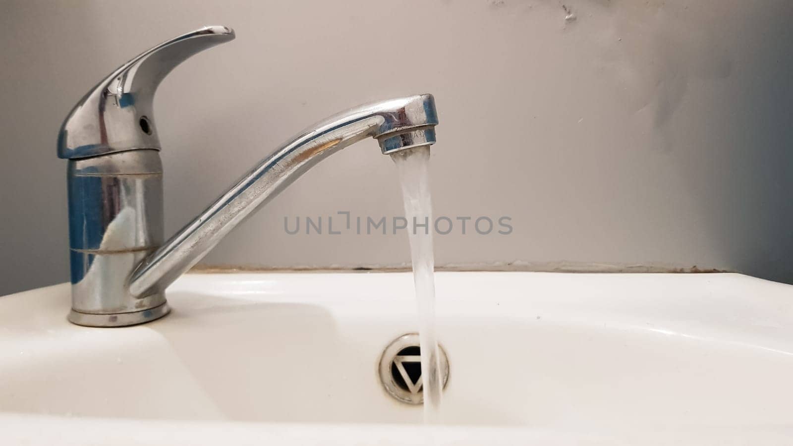 Old and dirty faucet and white ceramic washbasin sink, concept of cleaning, repairing or replacing a bathroom, toilet