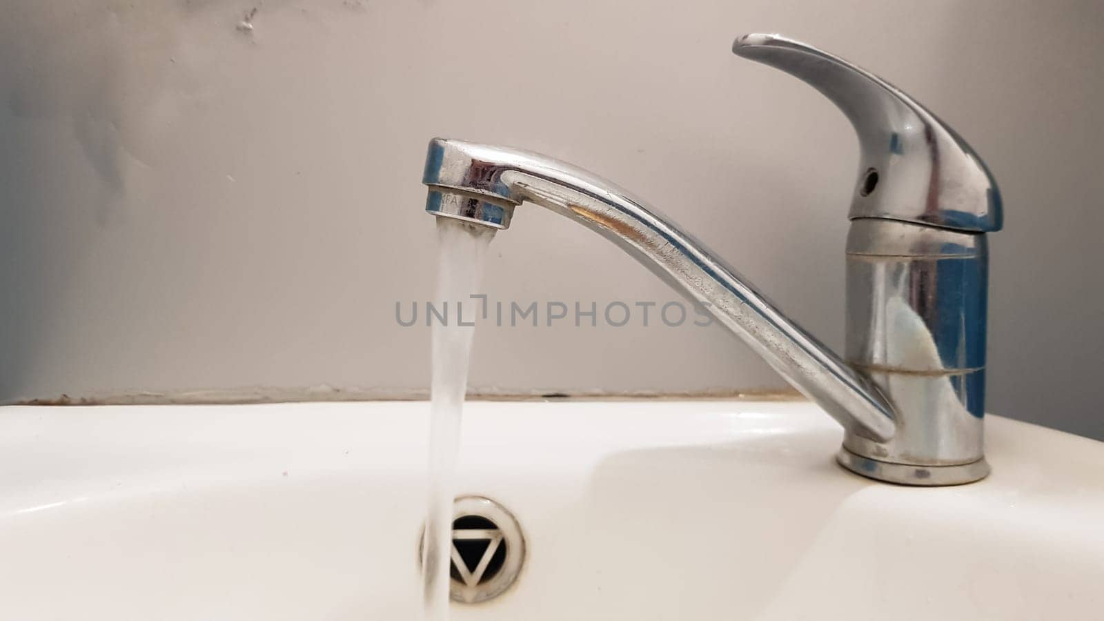Old and dirty faucet and white ceramic washbasin sink, concept of cleaning, repairing or replacing a bathroom, toilet