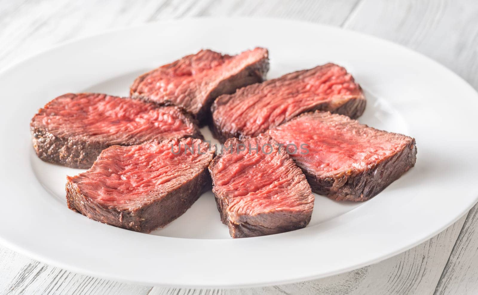 Tender fillet mignon steak, perfectly cooked, sliced, and elegantly presented on a plate