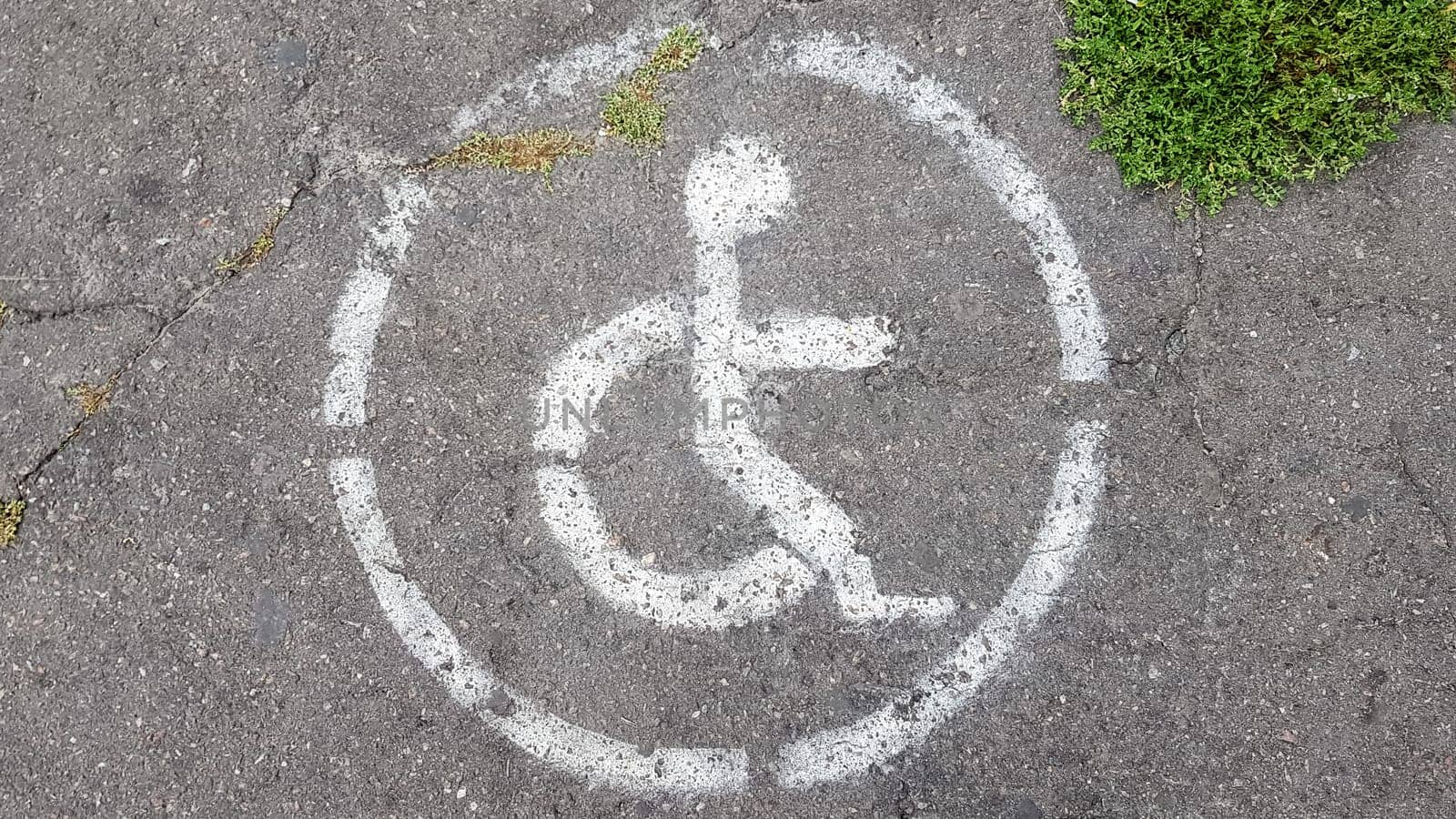 Disabled parking symbol. Disabled bay marked with a person in a wheelchair sign on gray asphalt in a large parking lot close up. view from above.