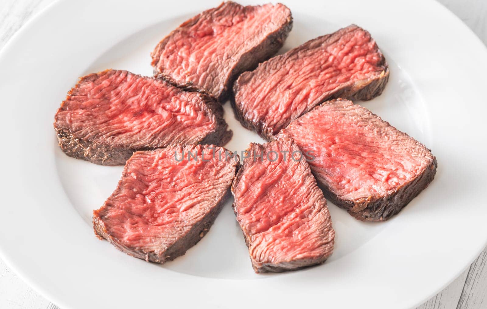 Tender fillet mignon steak, perfectly cooked, sliced, and elegantly presented on a plate
