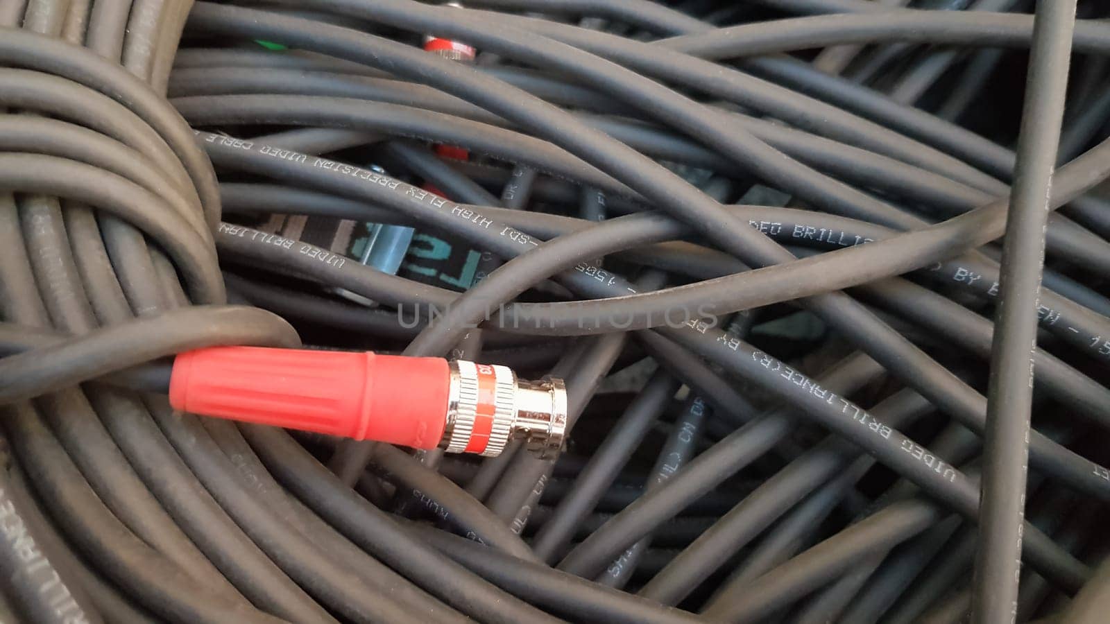 A roll of black cable closeup with a red plug