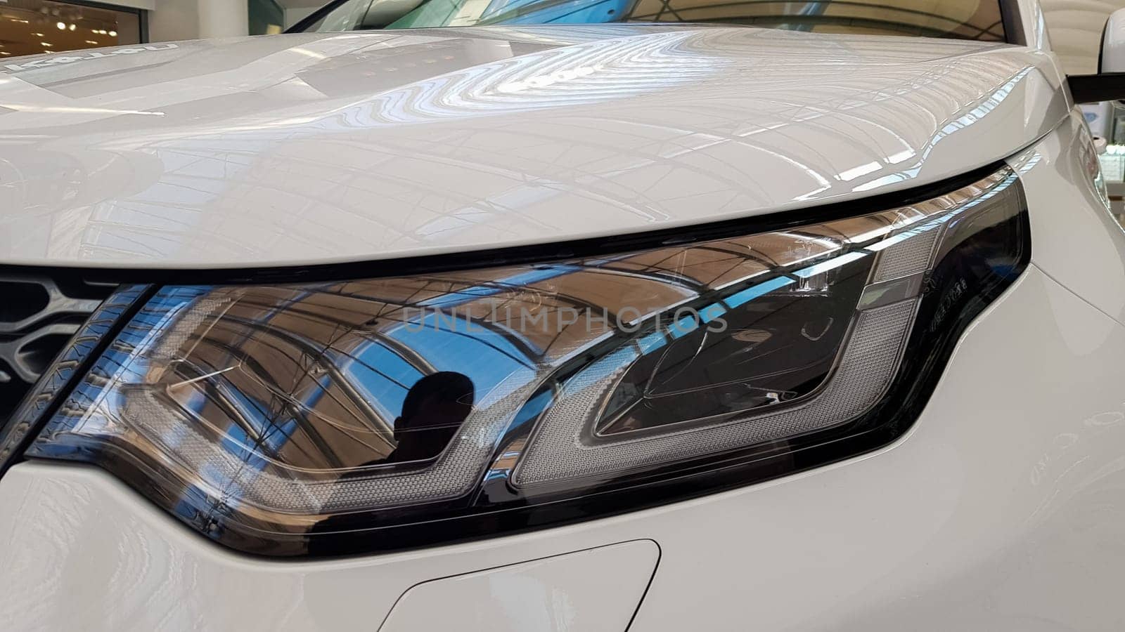 Ukraine, Kiev - March 27, 2020: Land Rover Discovery Sport shiny modern white car at the exhibition. Body, headlights close-up, rear and front view, chrome grille, car logo