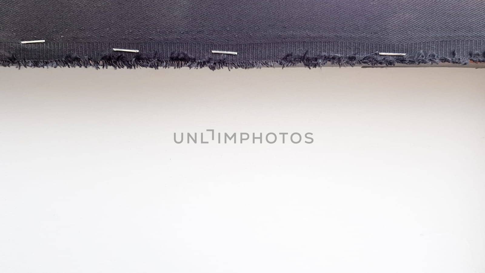 White background with a black fabric stripe punched with staples to a wooden plank. Abstract background with copy space