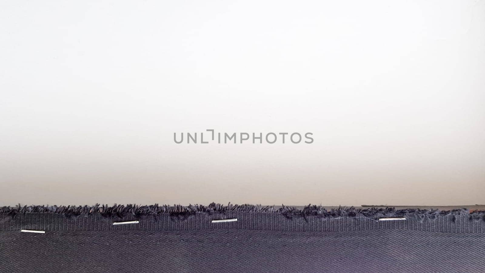 White background with a black fabric stripe punched with staples to a wooden plank. Abstract background with copy space