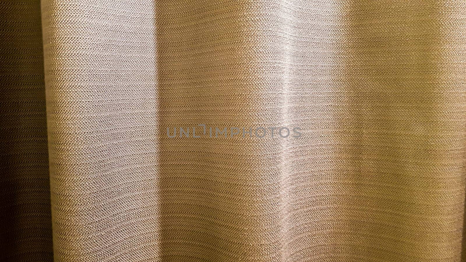 Brown pleated fabric. Thick, pleasant to the touch curtains close-up. Variant of interior decoration. Sewing product.