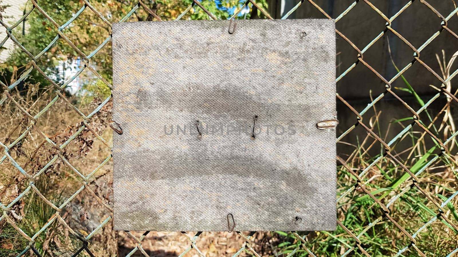 Old cracked square wooden plate on an old metal mesh. Place for your text or logo. Copy space.
