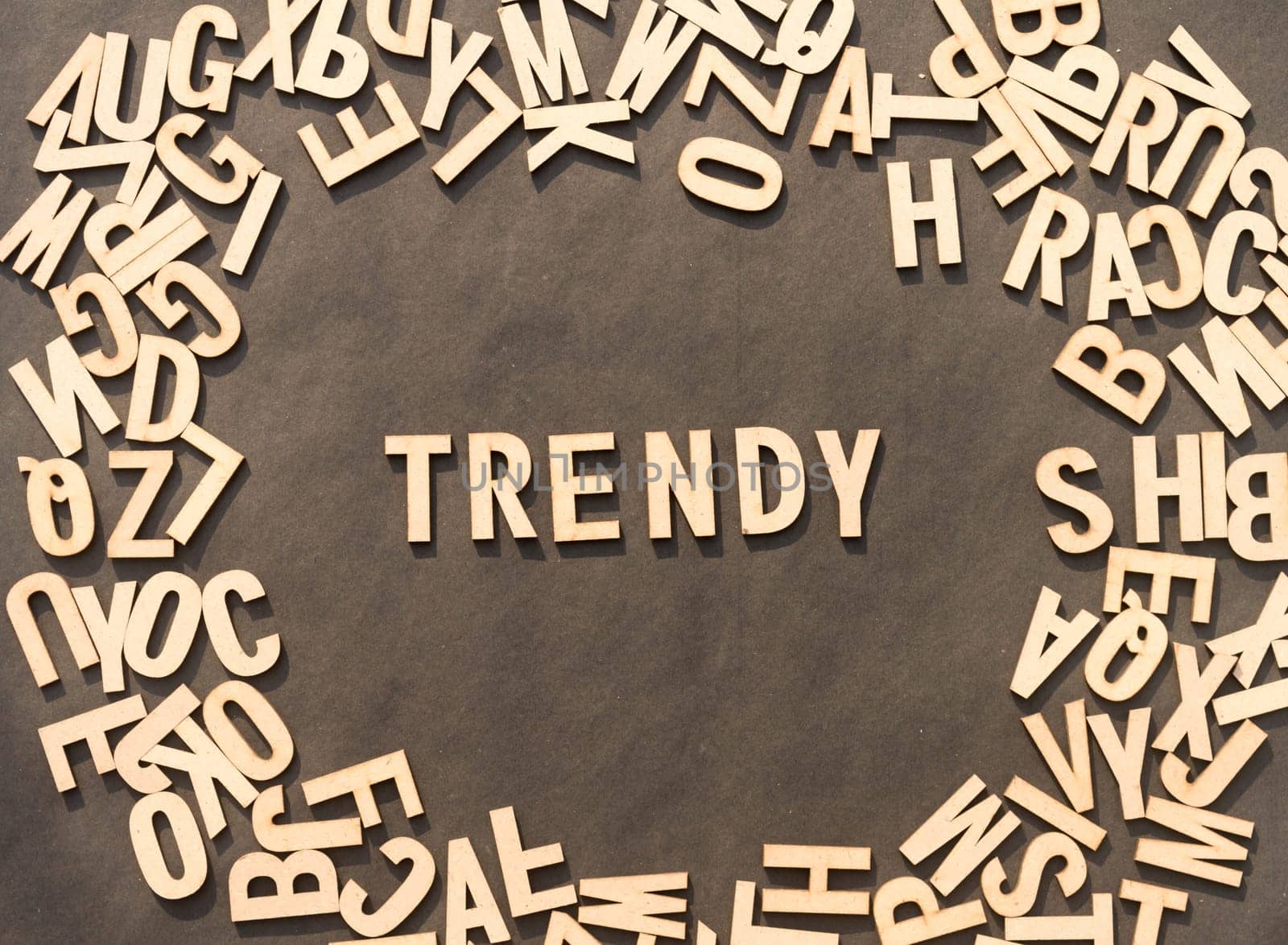 Trendy Word In Wooden Cube Alphabet Letters Top View On A rustic paper Background.