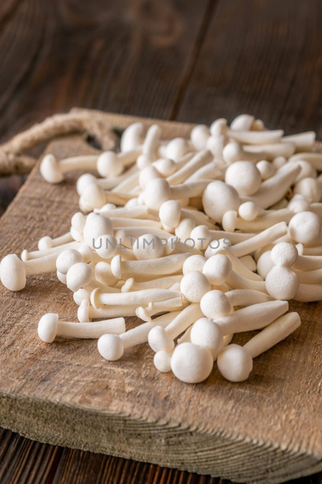 A delicate cluster of bunapi-shimeji mushrooms resting on a wooden surface