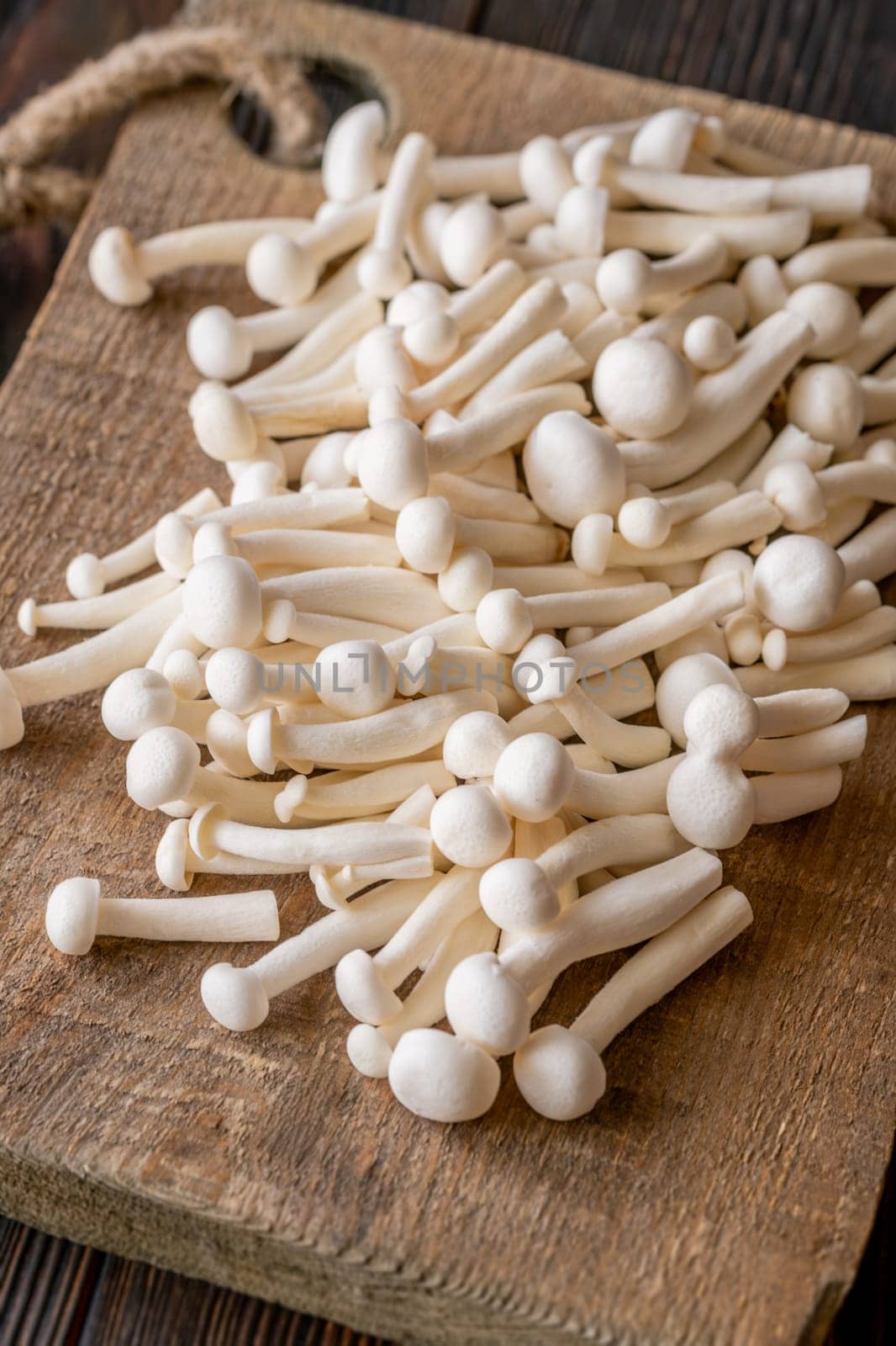 A delicate cluster of bunapi-shimeji mushrooms resting on a wooden surface