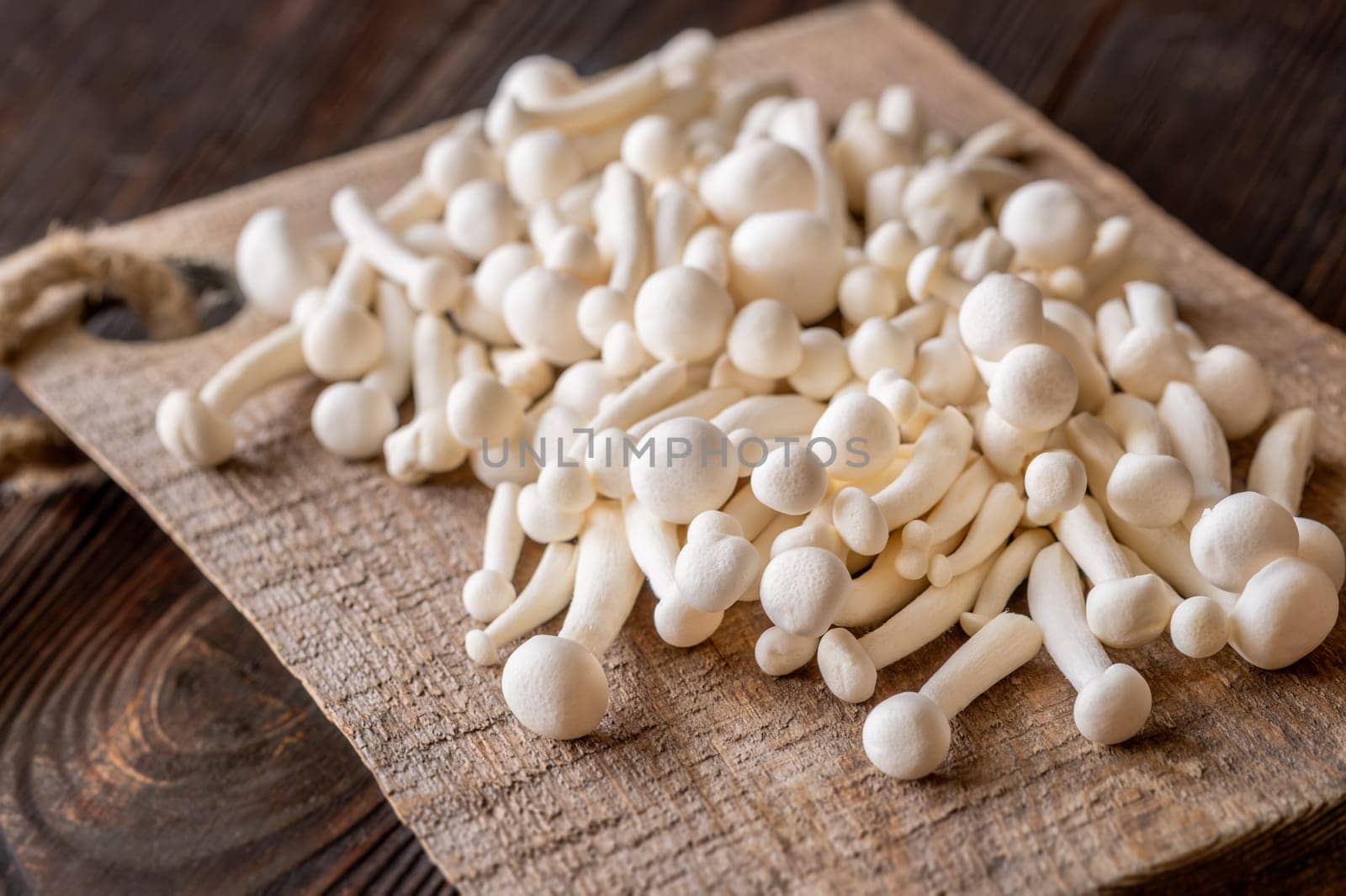 A delicate cluster of bunapi-shimeji mushrooms resting on a wooden surface
