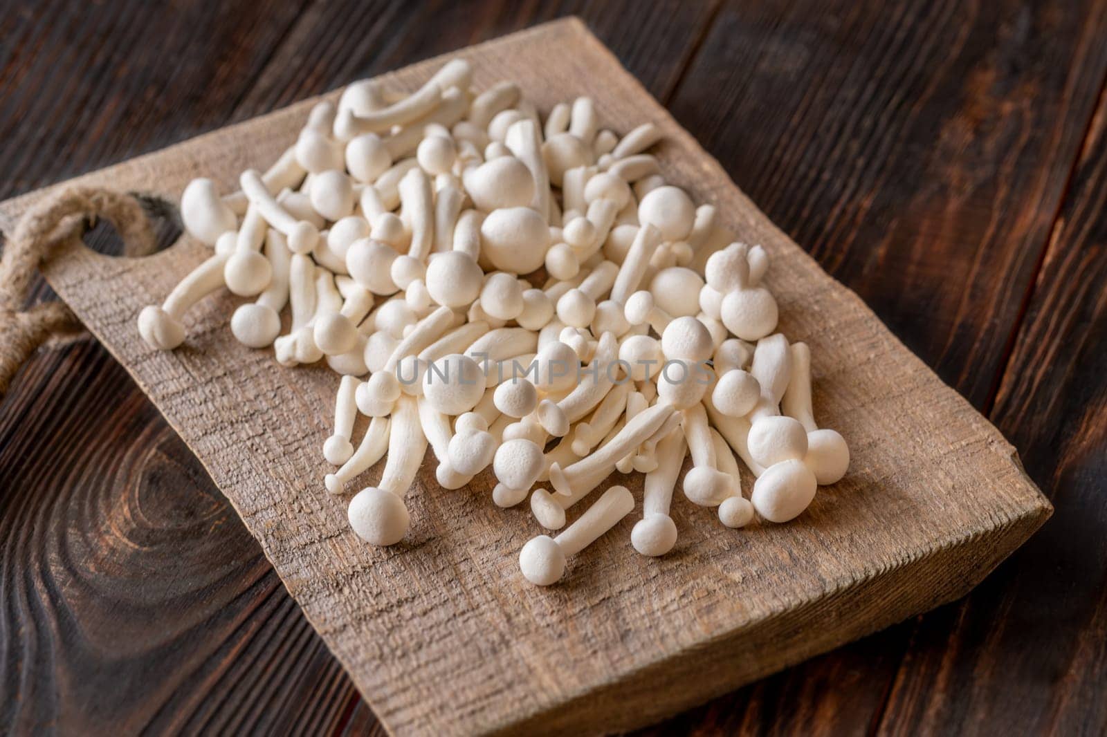 A delicate cluster of bunapi-shimeji mushrooms resting on a wooden surface
