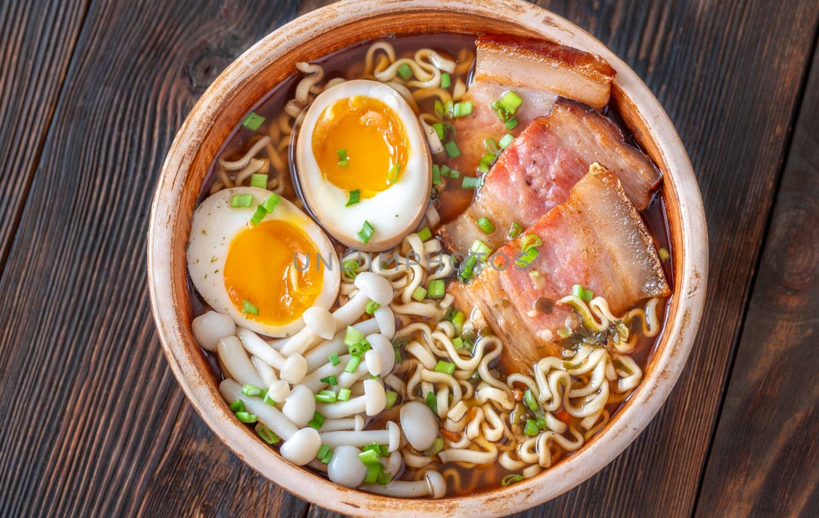 A steaming bowl of ramen filled with noodles, tender pork, and savory toppings