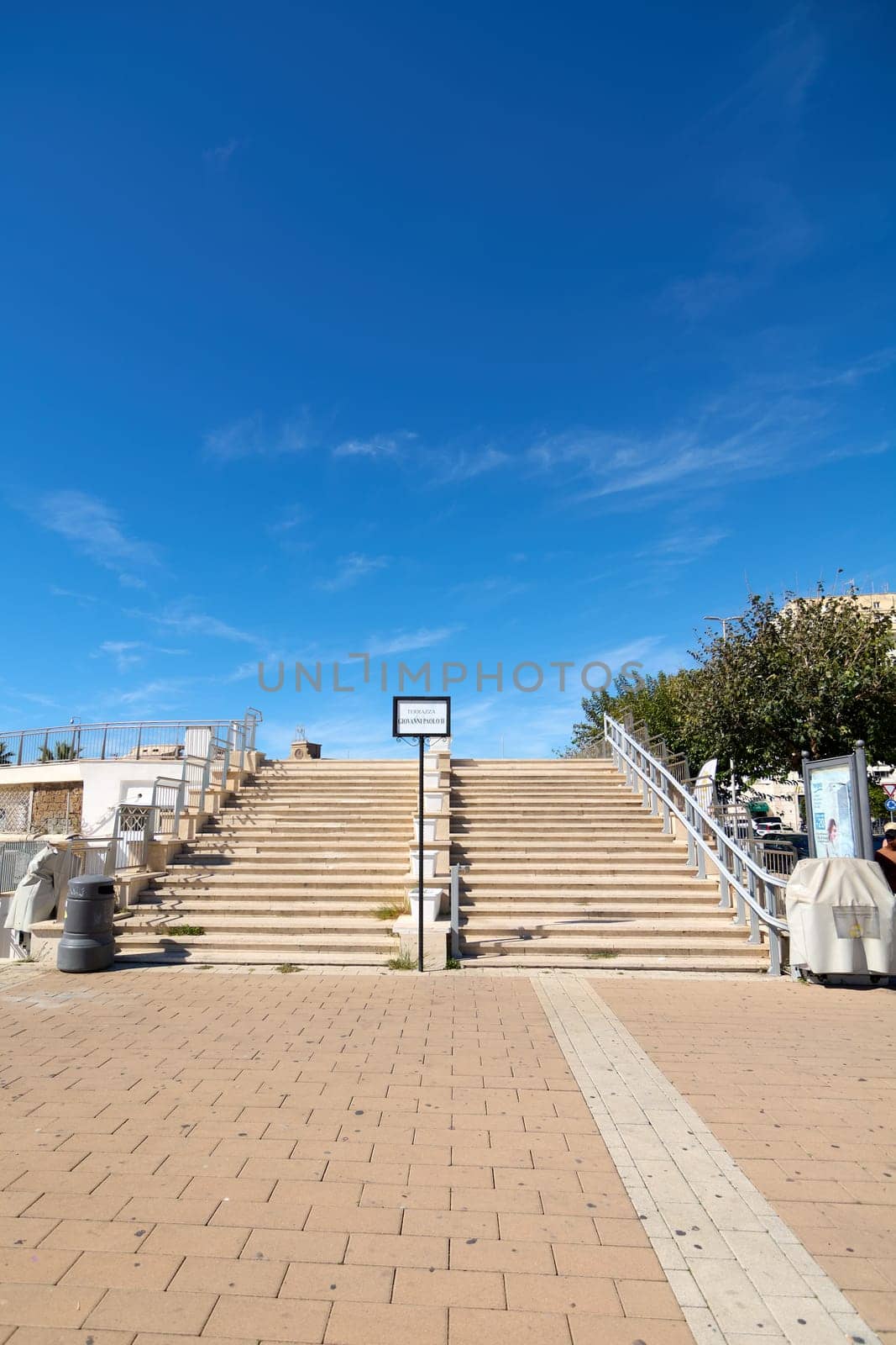 Civitavecchia. Italy - January 27, 2025: Stone steps ascending to the Giovanni Paolo II terrace in Civitavecchia, Italy. The scene is bright and inviting, perfect for travel and architecture themes.