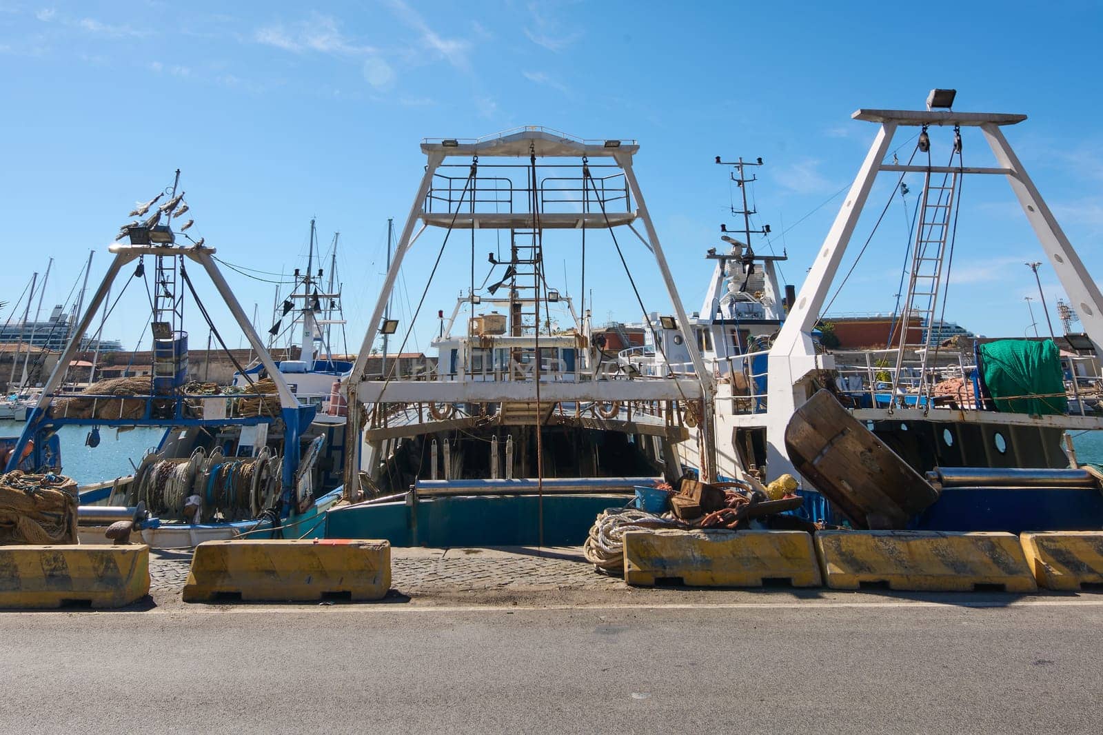 Fishing boats at dock in Civitavecchia, equipped with various fishing gear including nets and reels. This image portrays the detailed and organized setup of fishing operations