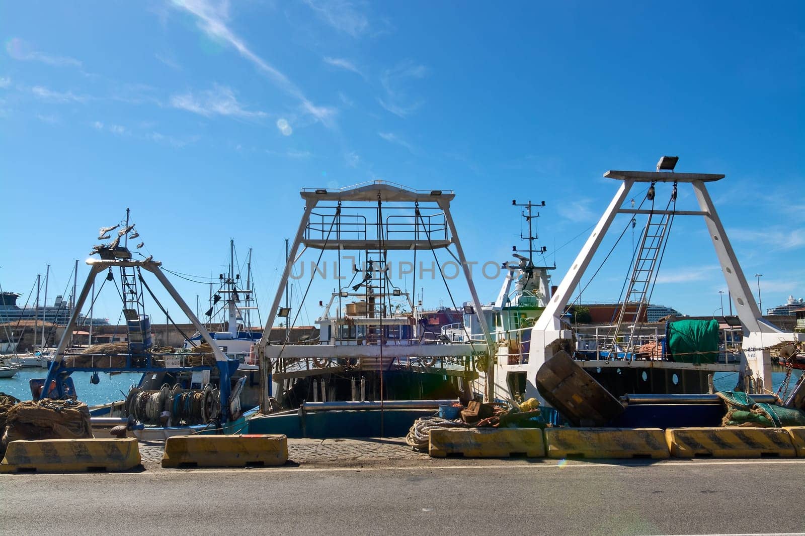 Dockside view of fishing boats in Civitavecchia, Italy, with equipment and nets visible. This image highlights the complexity and daily life in the fishing industry