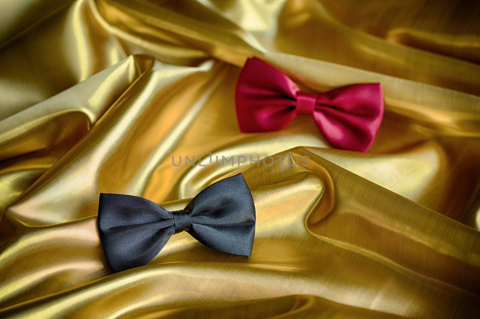 Red and black bow ties on draped golden satin