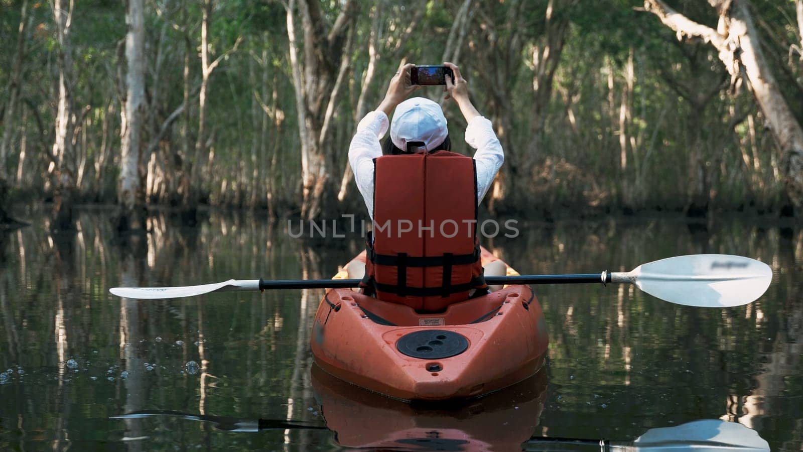 Young adult woman kayaking canoe boat on a lake she take photo natural scenery by smartphone on summer day, adventure travel leisure enjoying concept, lifestyle sport vacation