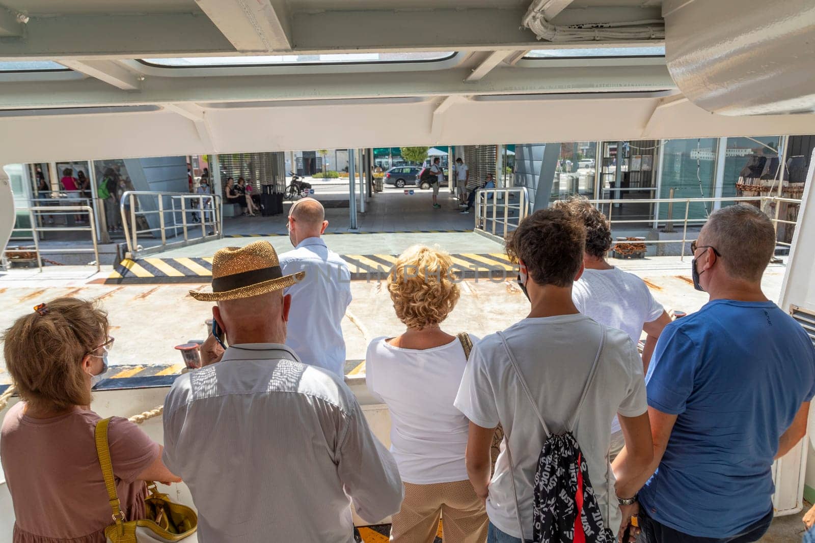Venice, Italy - July 5 2021: the ferry anchors at the ferry stop Lido with tourists and local people on board of the vaporetto.