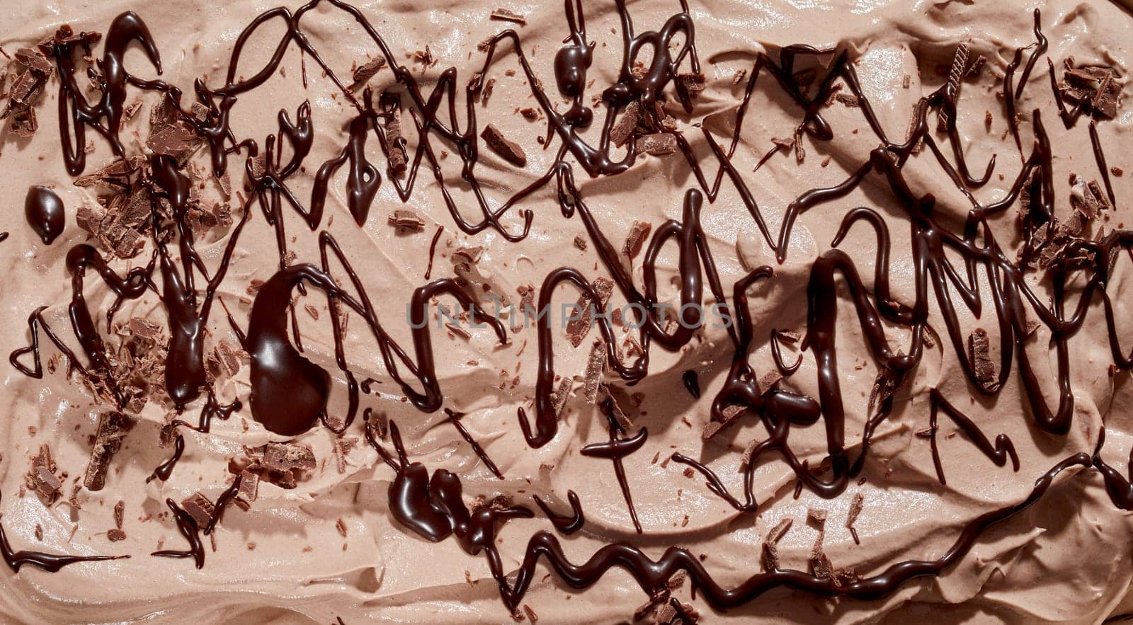 Chocolate sauce drizzled over delicious creamy ice-cream or frozen yogurt in a close up full frame background texture for menu or design concepts