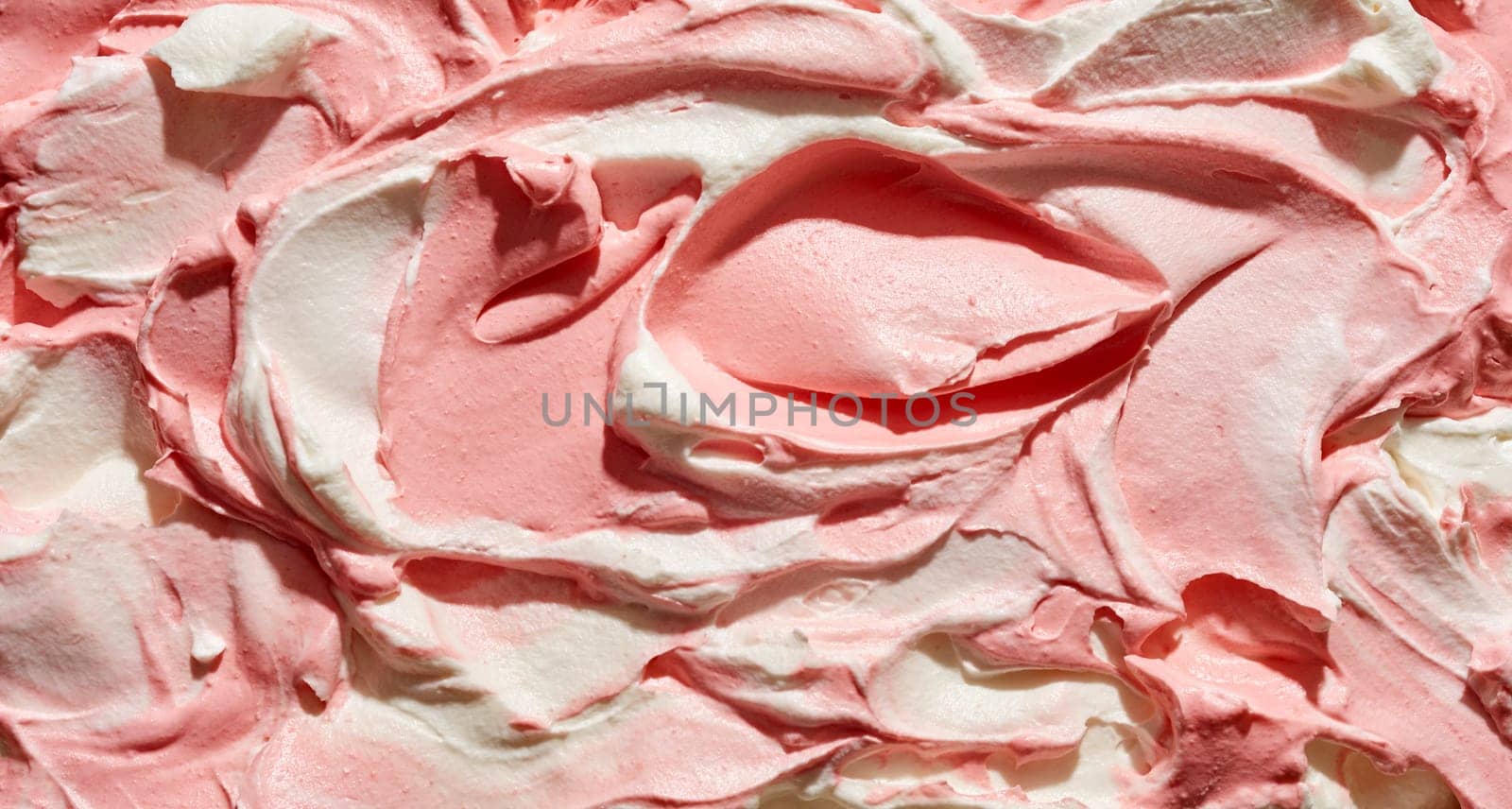 Creamy strawberry and vanilla ice cream for a tasty summer treat in a close up full frame background texture of the surface of the dessert with swirling ridges