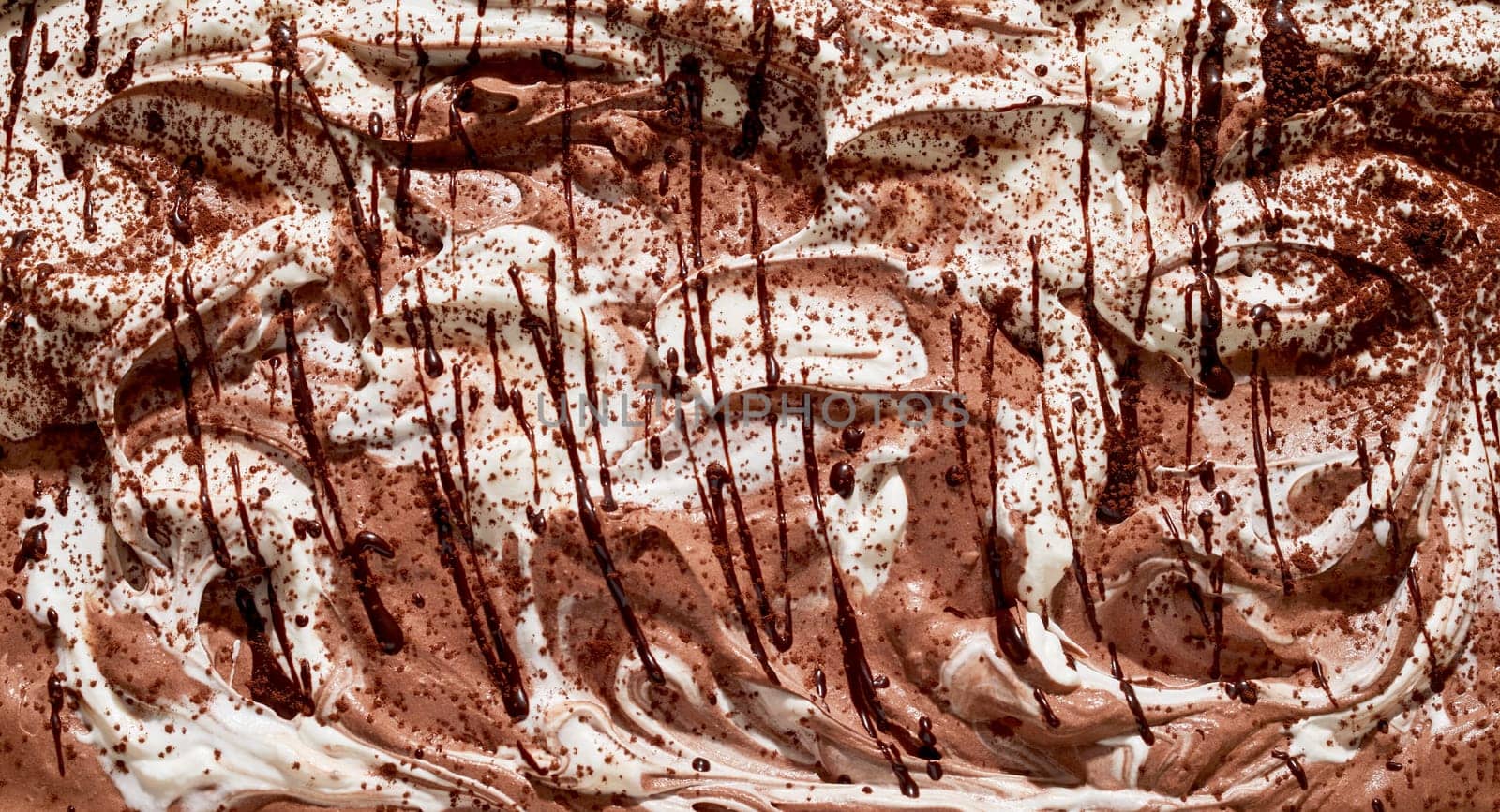 Variegated dual flavor vanilla and chocolate ice-cream background texture with a close up on the surface of the dessert drizzled with chocolate sauce or syrup