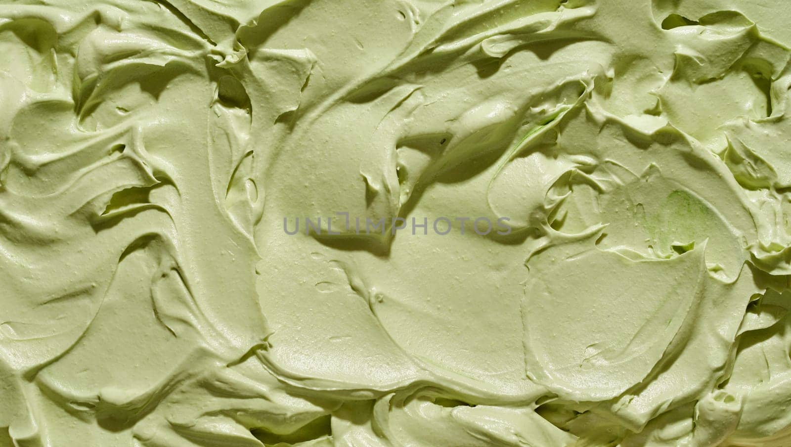 Full frame background texture of green pistachio nut ice-cream with abstract swirled pattern for menu advertising or catering concepts
