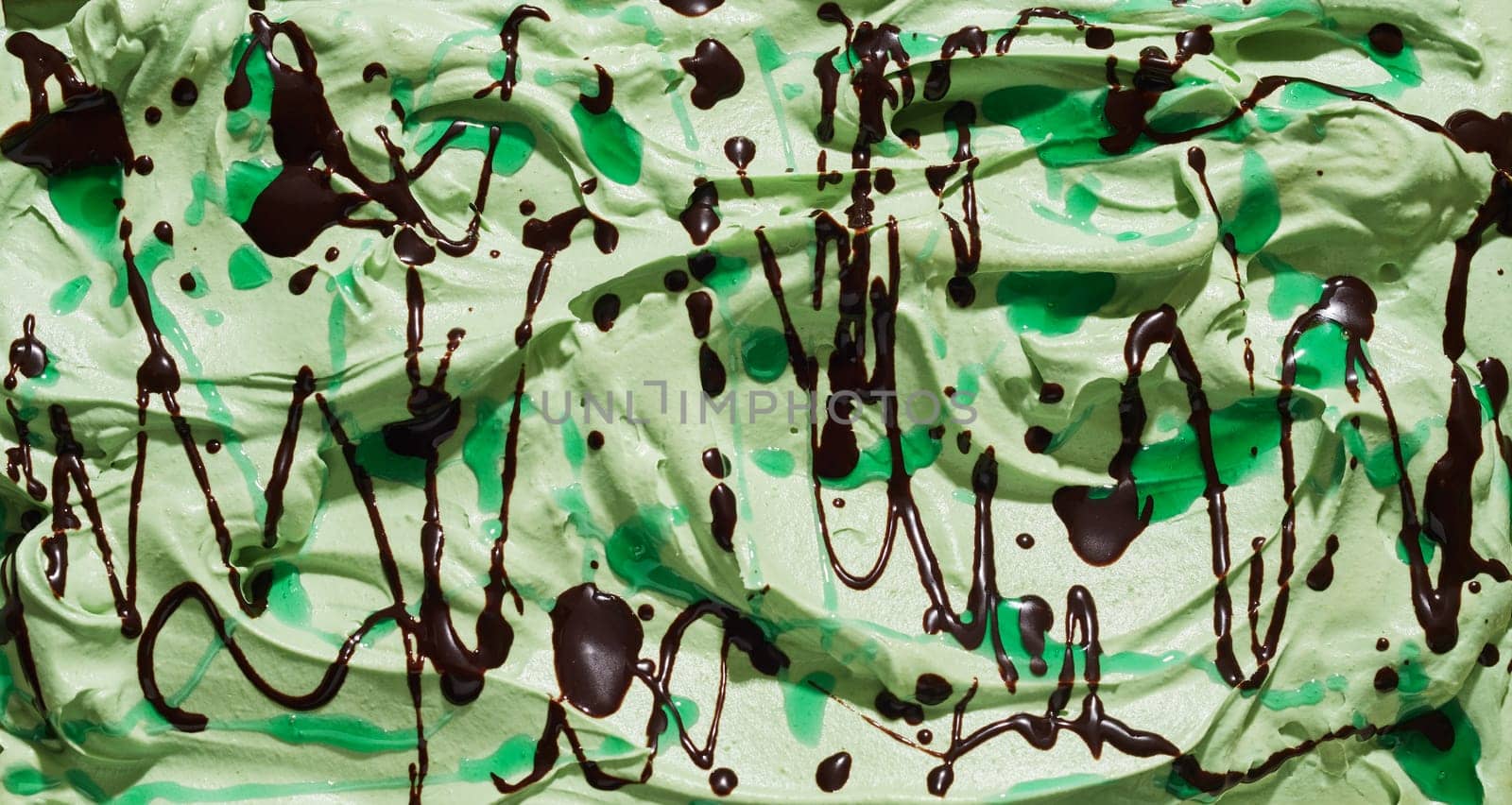 Tasty refreshing green mint ice cream with chocolate drizzle for a tasty summer treat in a close up full frame background texture for menu advertising
