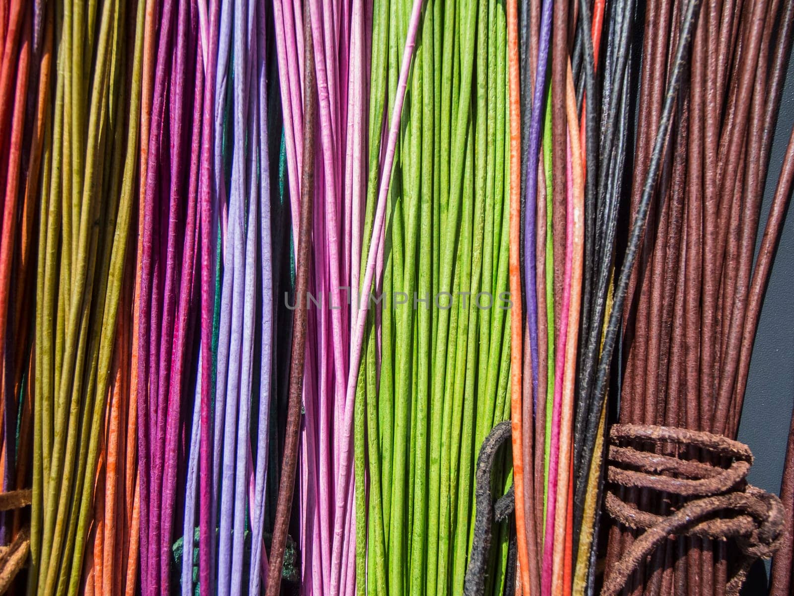 Red and orange colored leather cords with knots on a table in the sunlight.